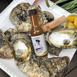 Oysters and oyster shells along with a bottle of Black Eyed Susan Spice Co Death by Chocolate Hot Sauce