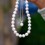 Pearl necklaces dangling from hand