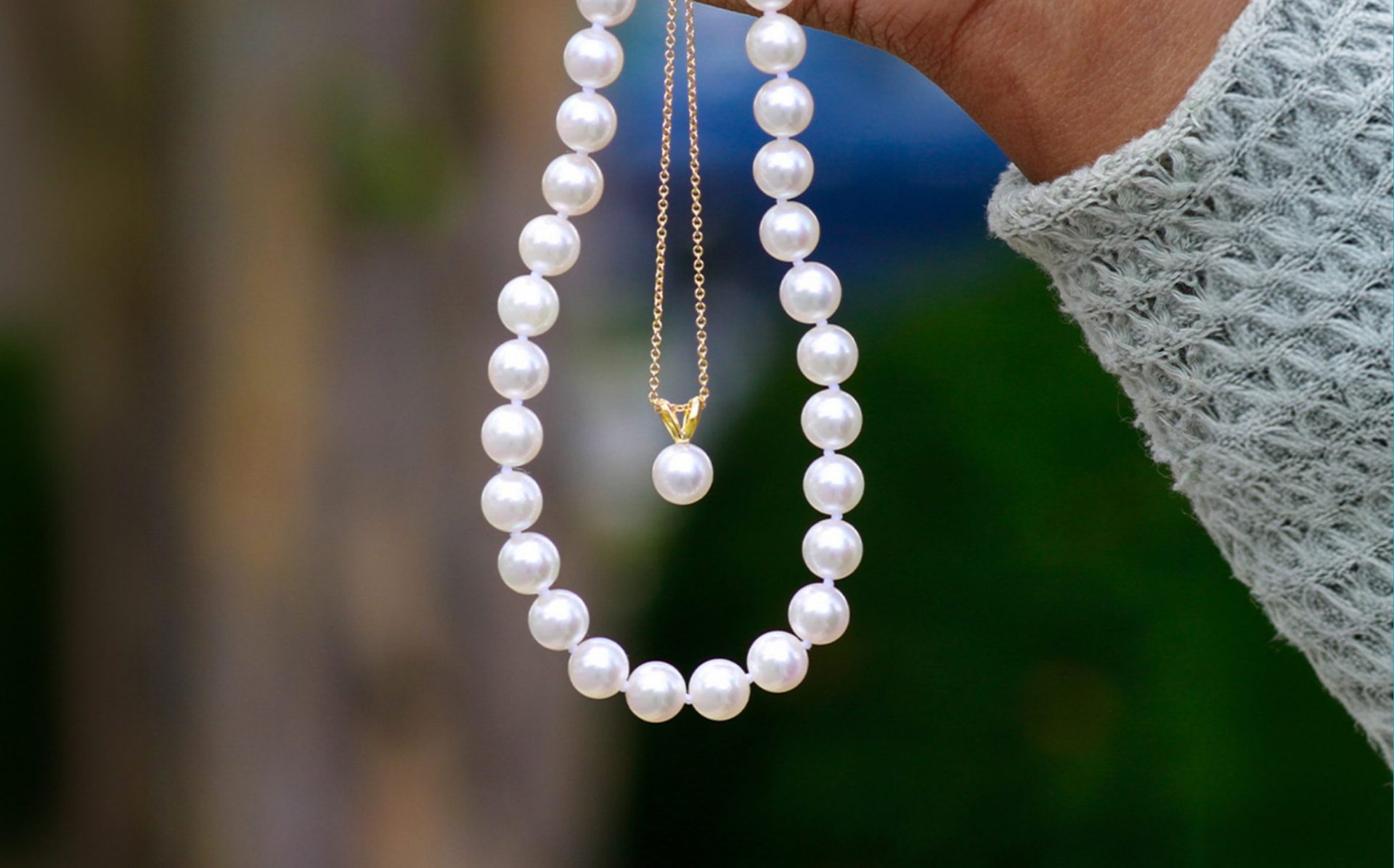 Pearl necklaces dangling from hand